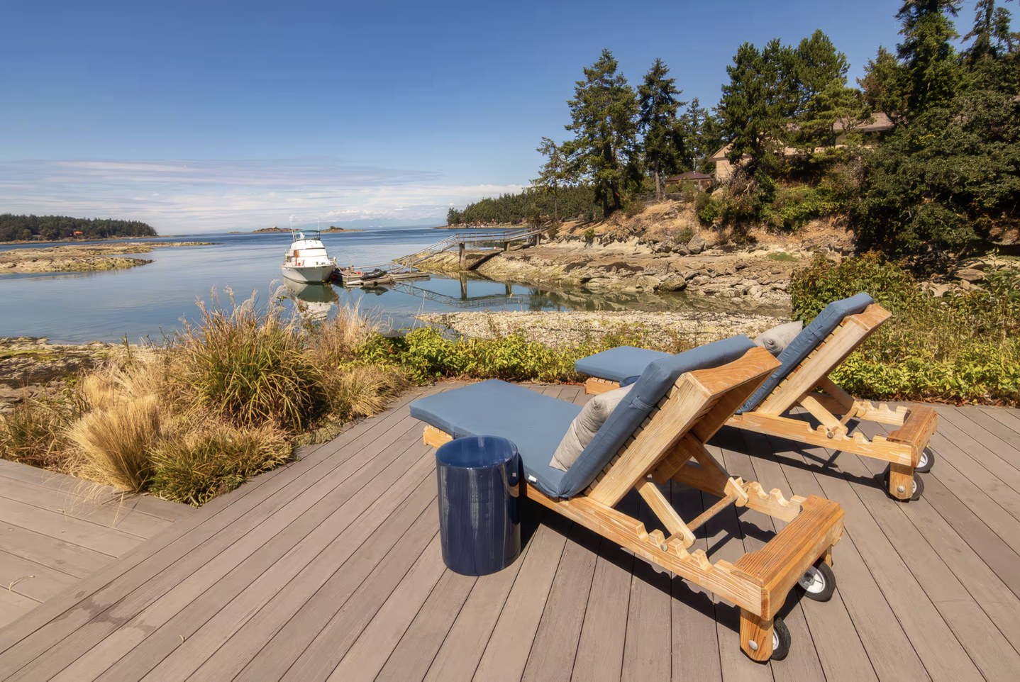 Teak loungers on the waterfront deck overlooking the bay and a moored yacht