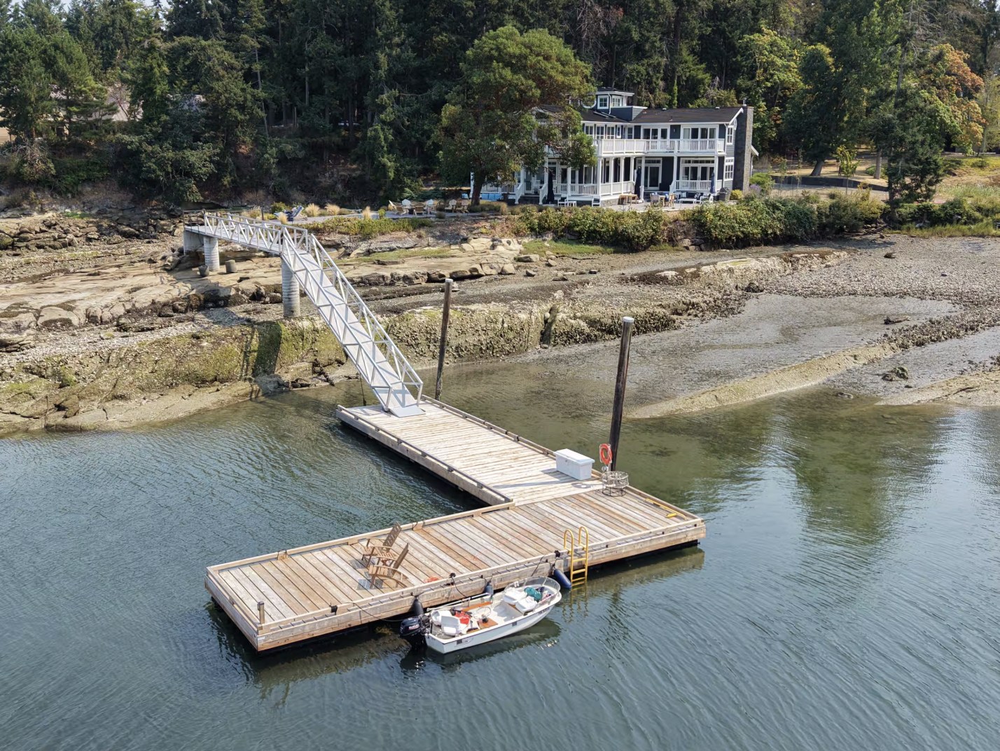 Aerial view of the deep-water dock and gangway below the house, with a small boat alongside