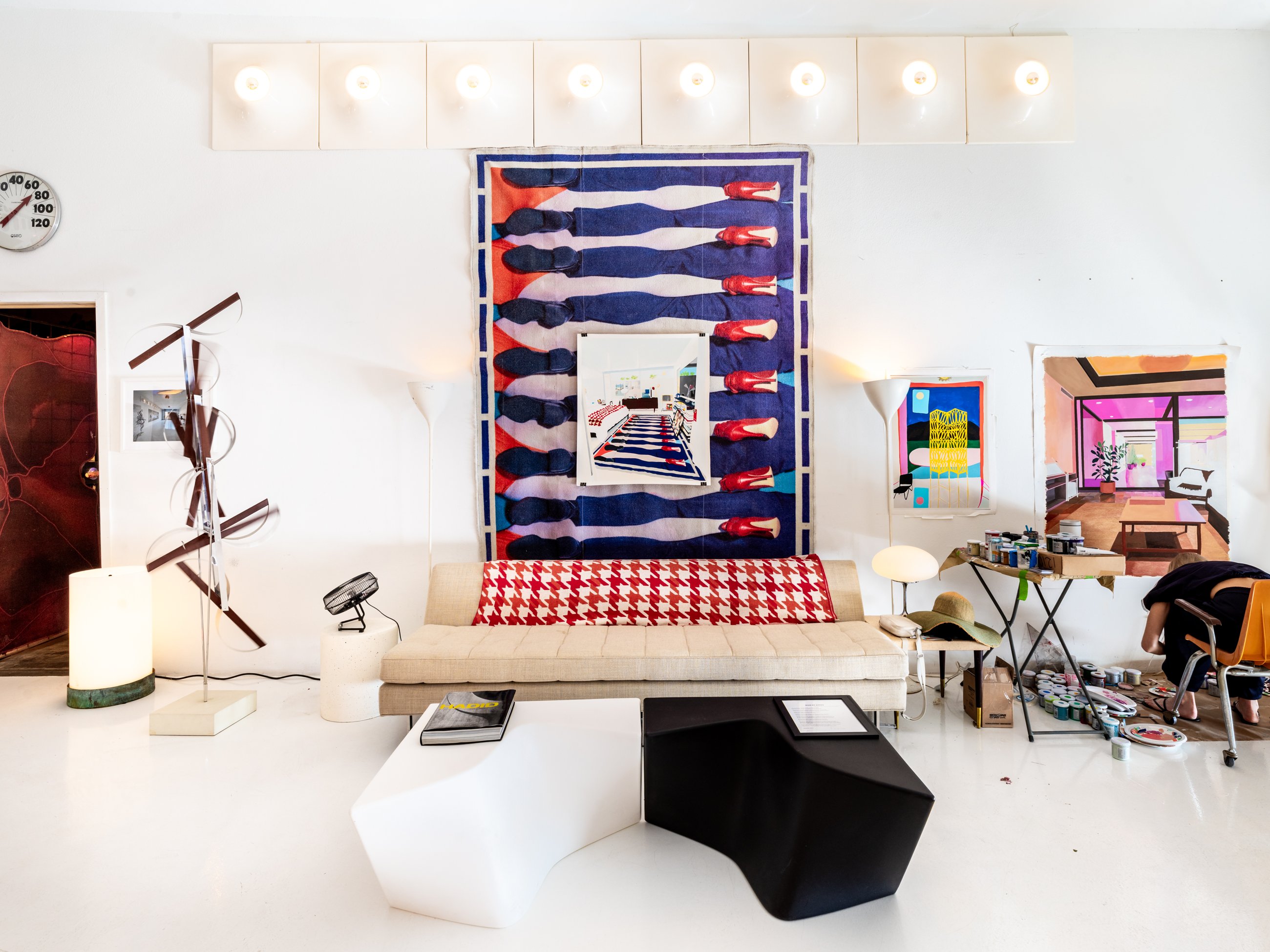 Lounge wall with a large textile work, sofa and sculptural tables