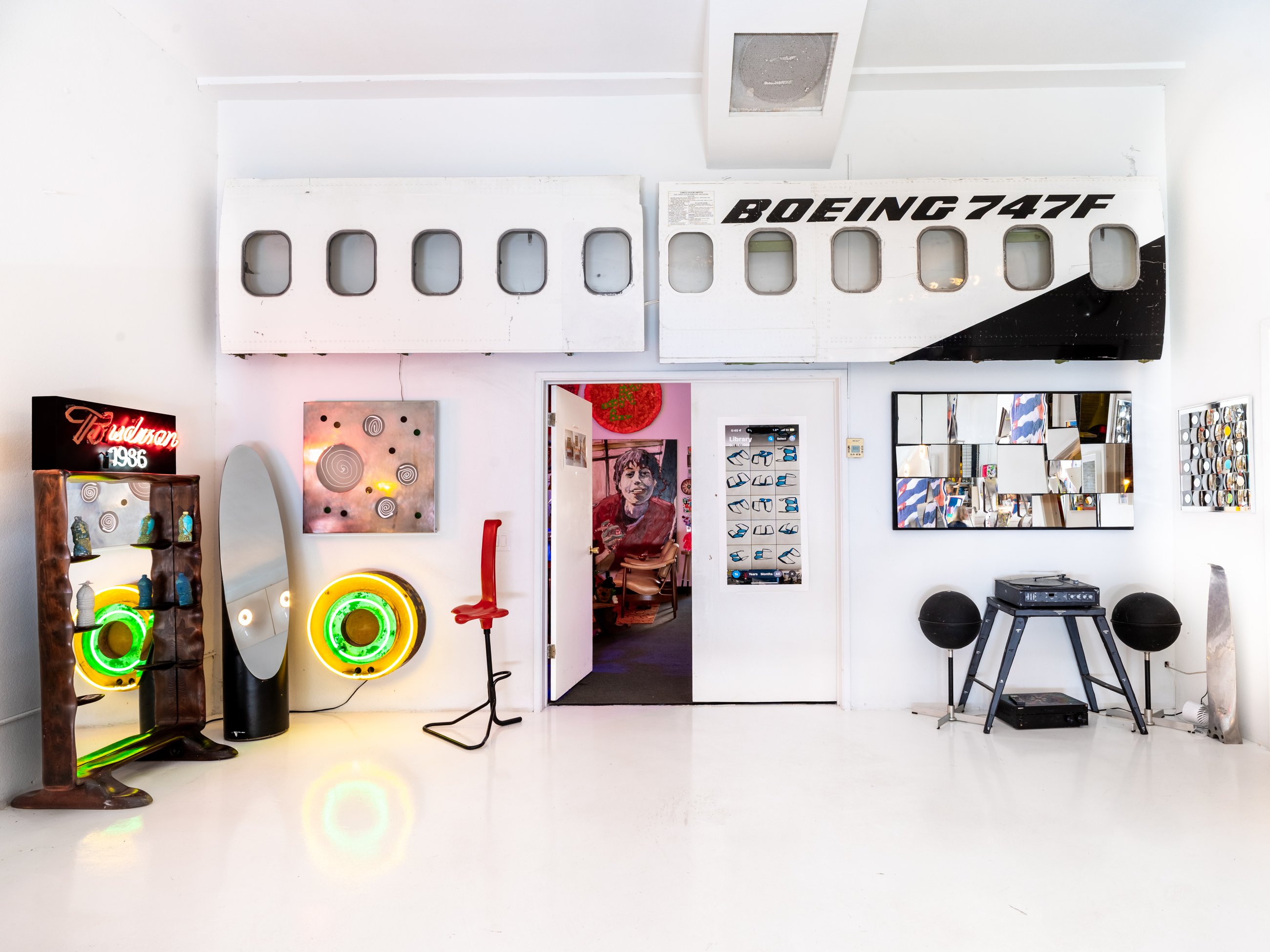 Boeing 747 fuselage panels above a wall of neon and design objects