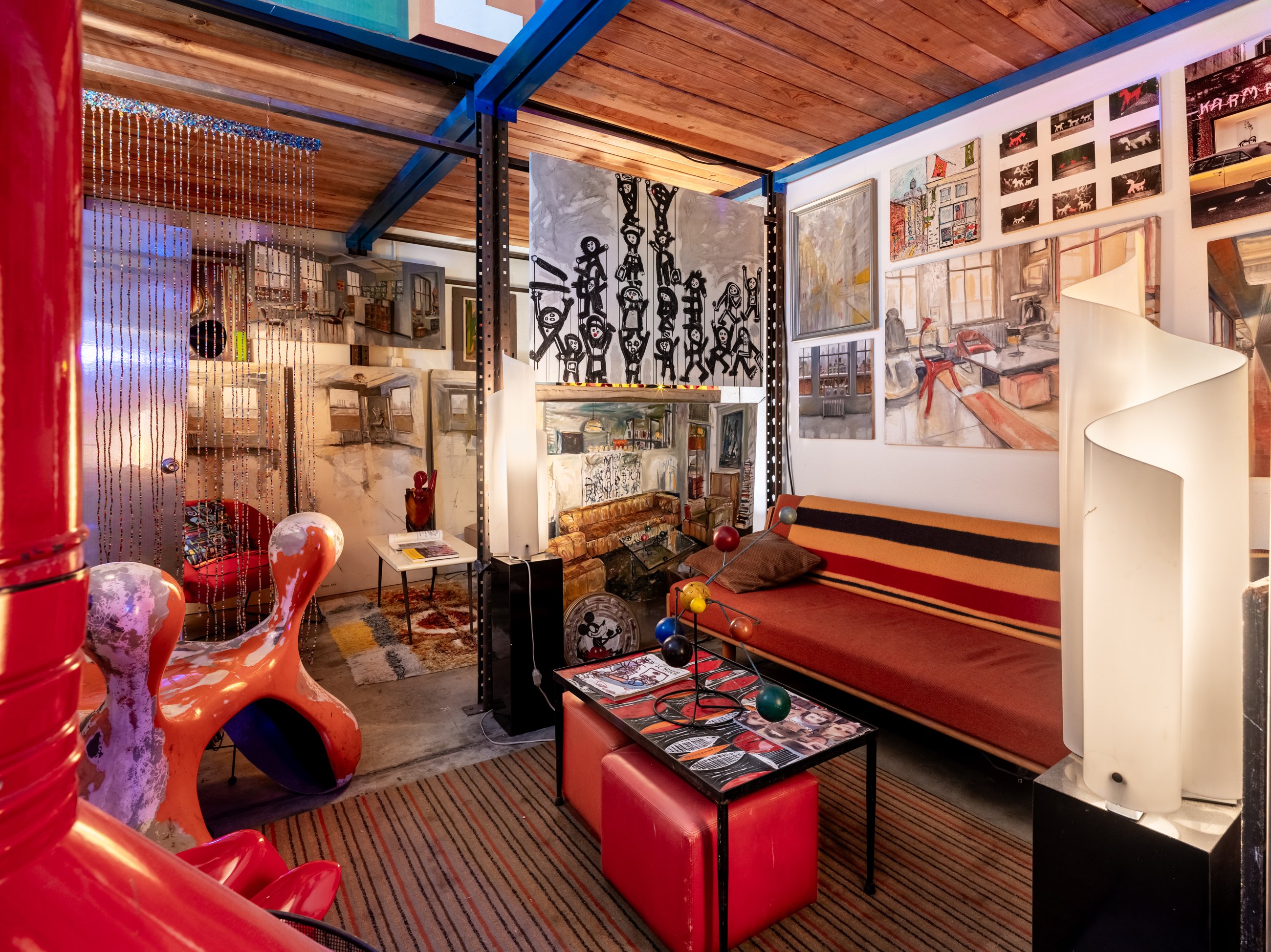 Loft lounge under timber beams with paintings and sculptural seating