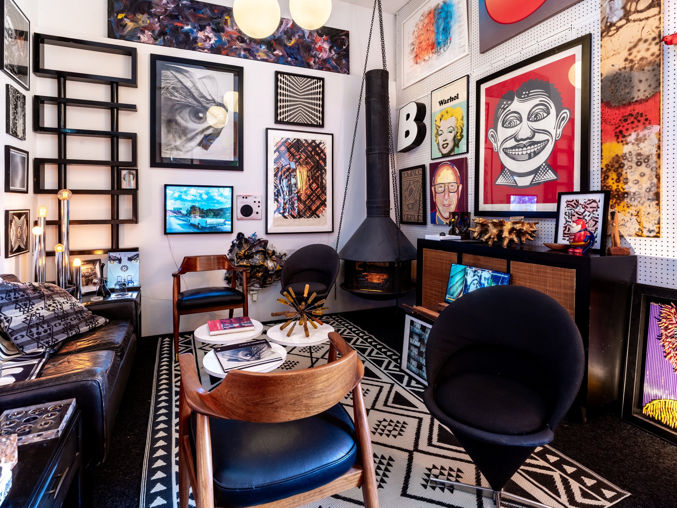Lounge with a hanging fireplace and a salon wall of framed art