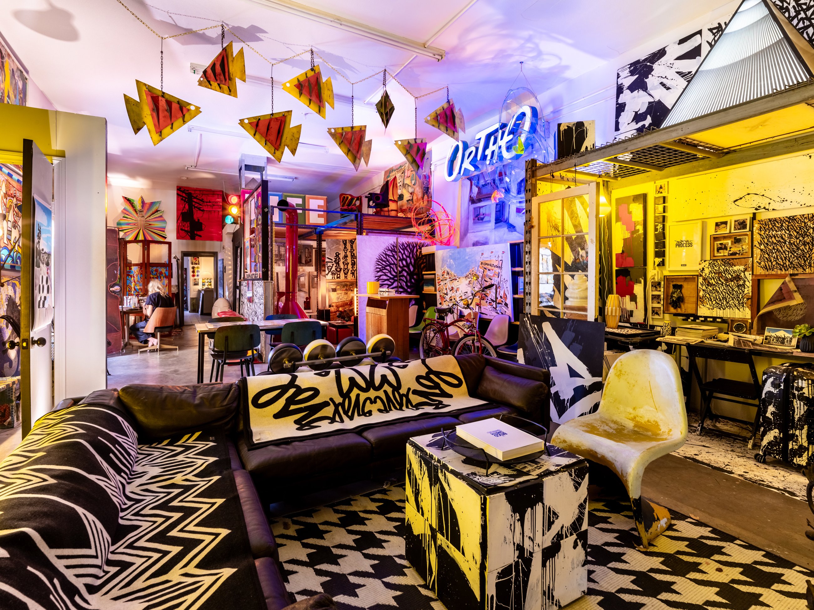 Open studio lounge under hanging metal sculptures and neon