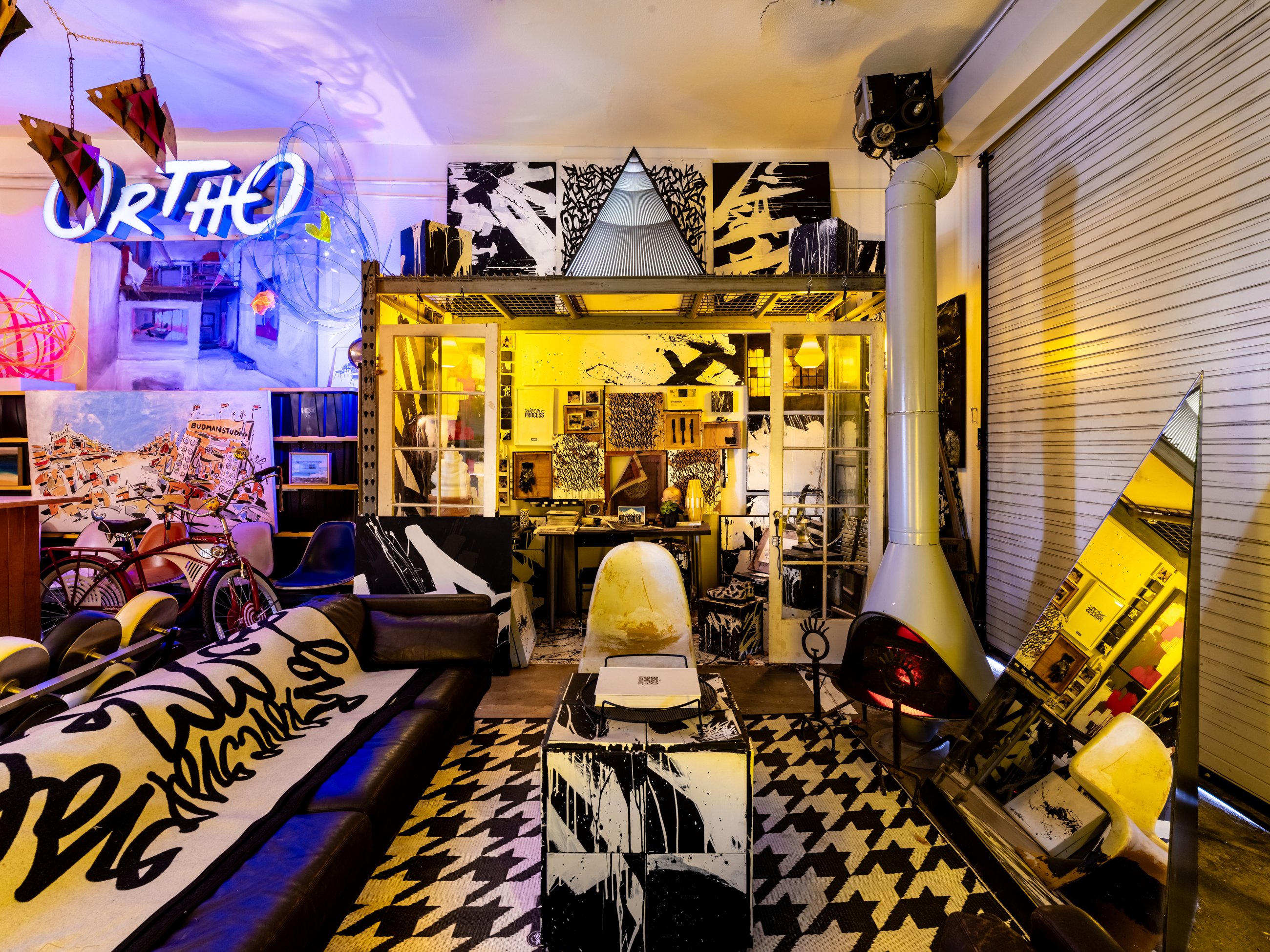Lounge with houndstooth rug, neon sign and a glass painting studio