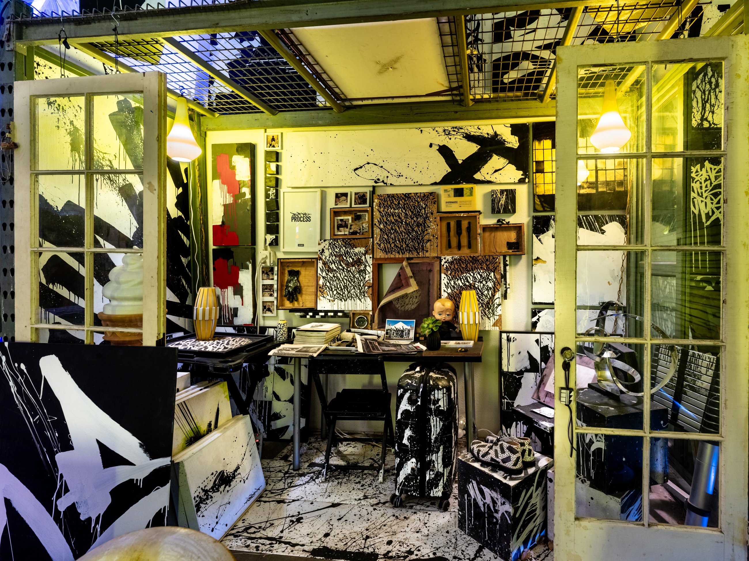 Painting studio behind glass doors, covered in black and white work