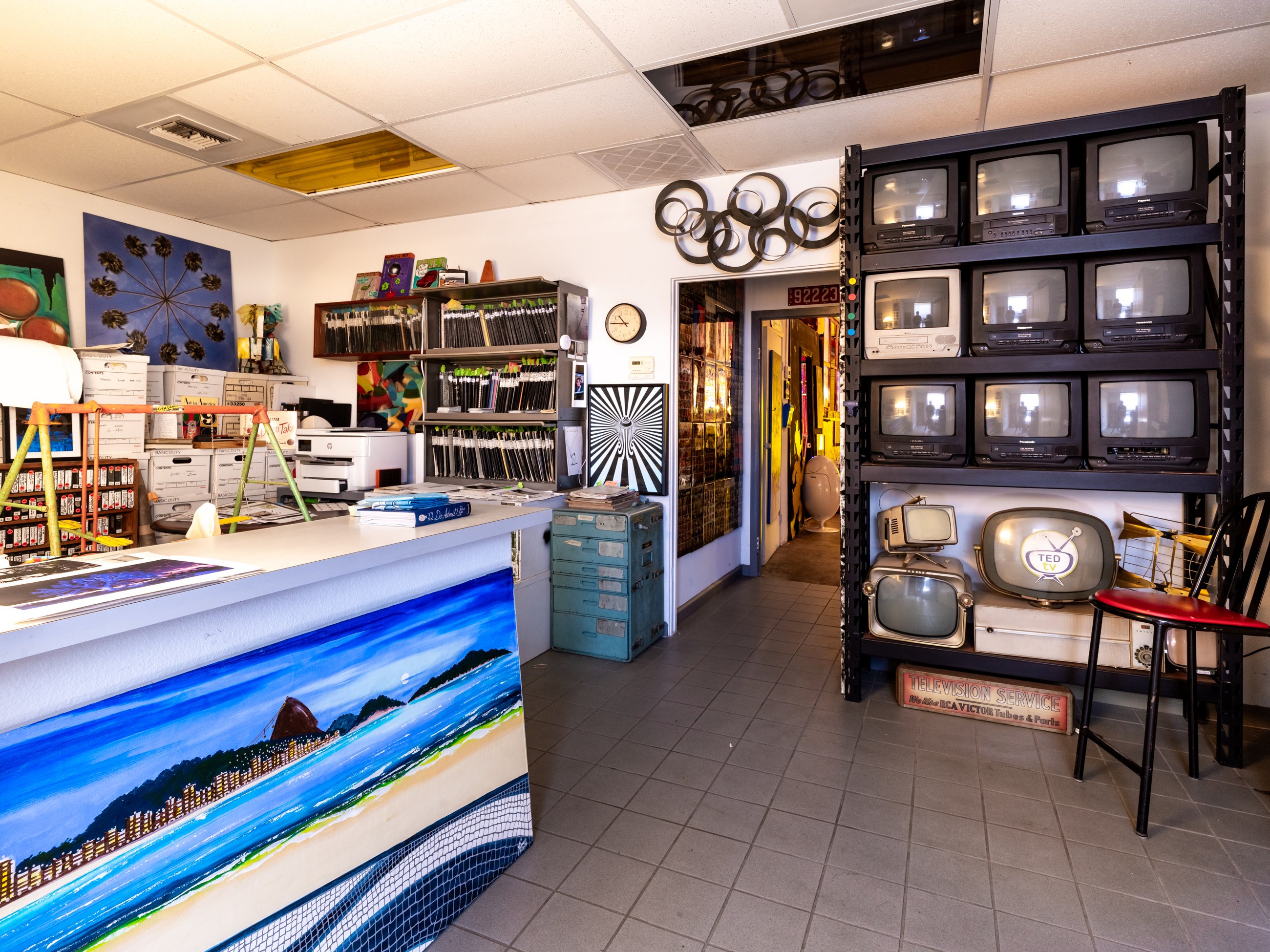 Front office with a wall of vintage televisions and a painted counter