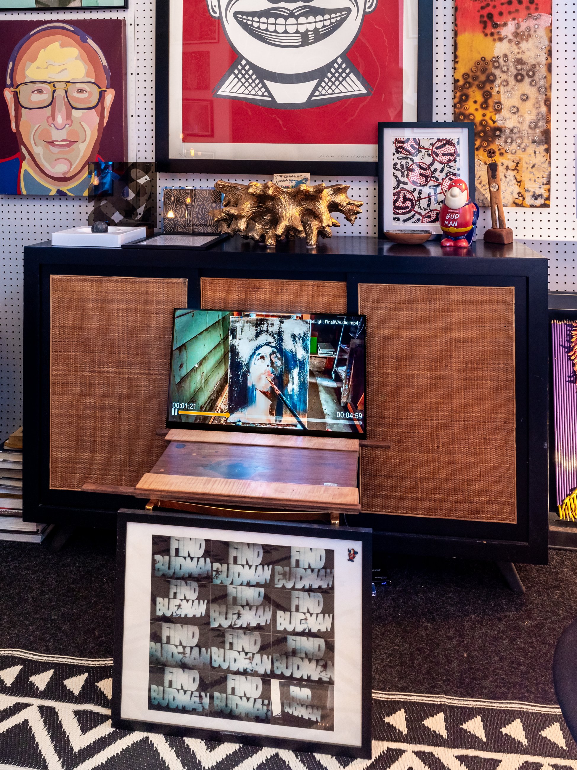 Cane media console against a pegboard wall of pop art