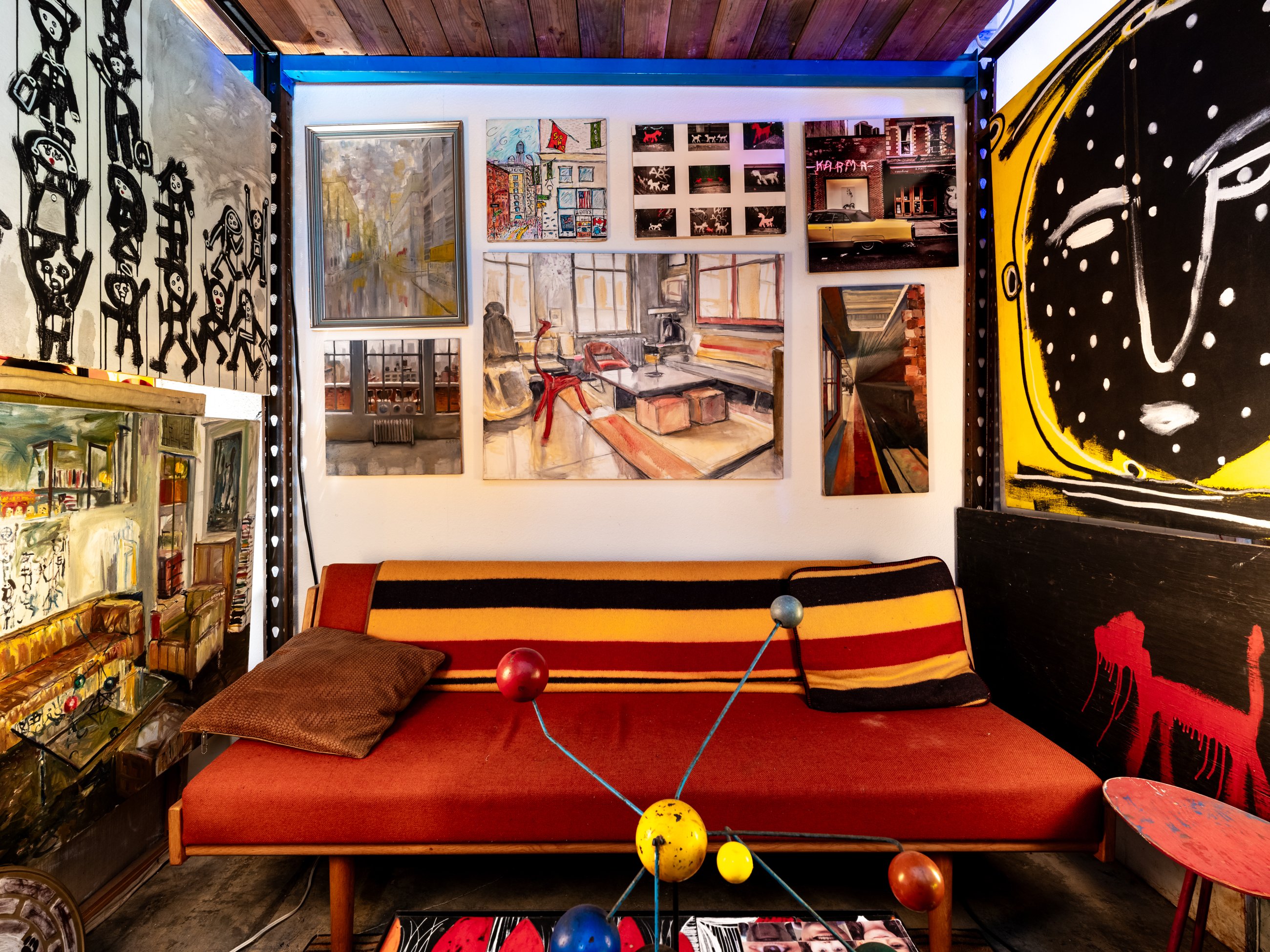 Striped daybed beneath a salon wall of city paintings