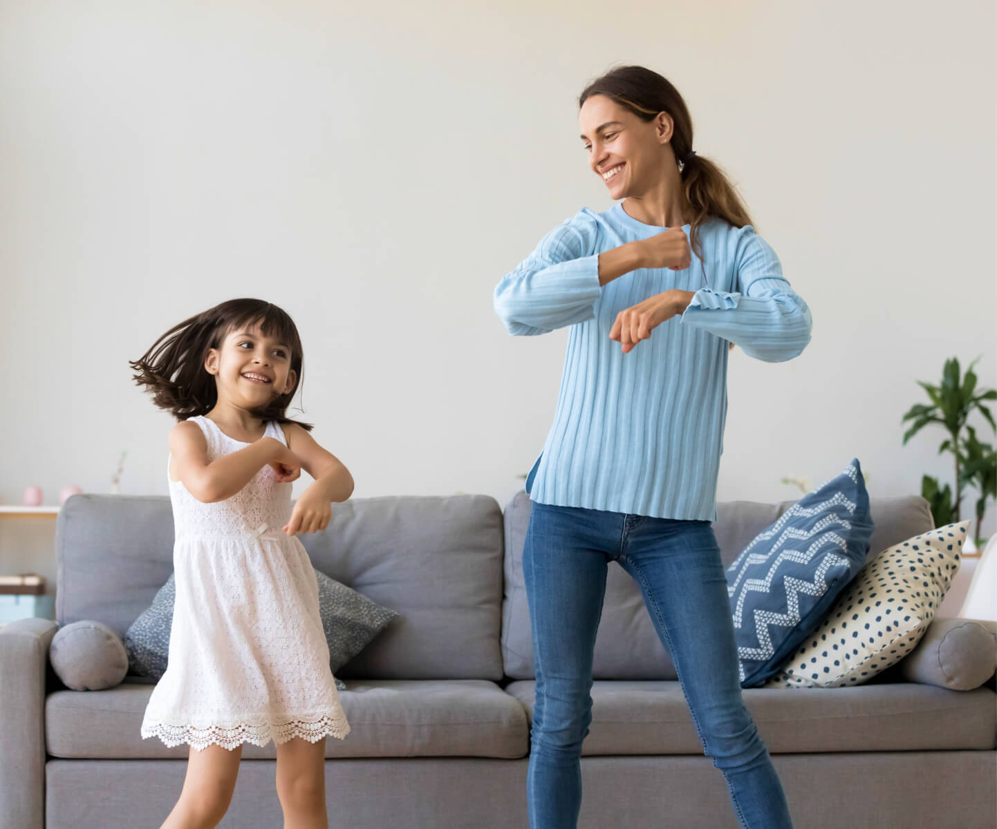 Mother and daughter dancing together in front of the sofa