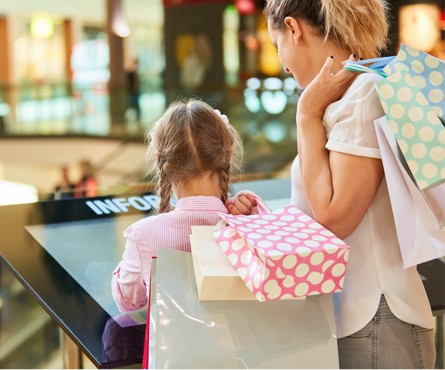 A mother and daughter interacting with a touch kiosk while shopping together