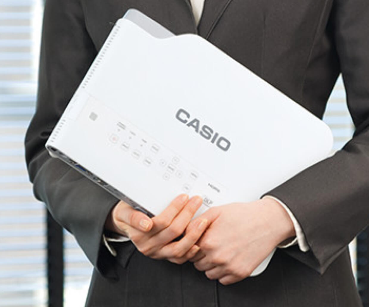 A pair of hands holding a white Casio projector