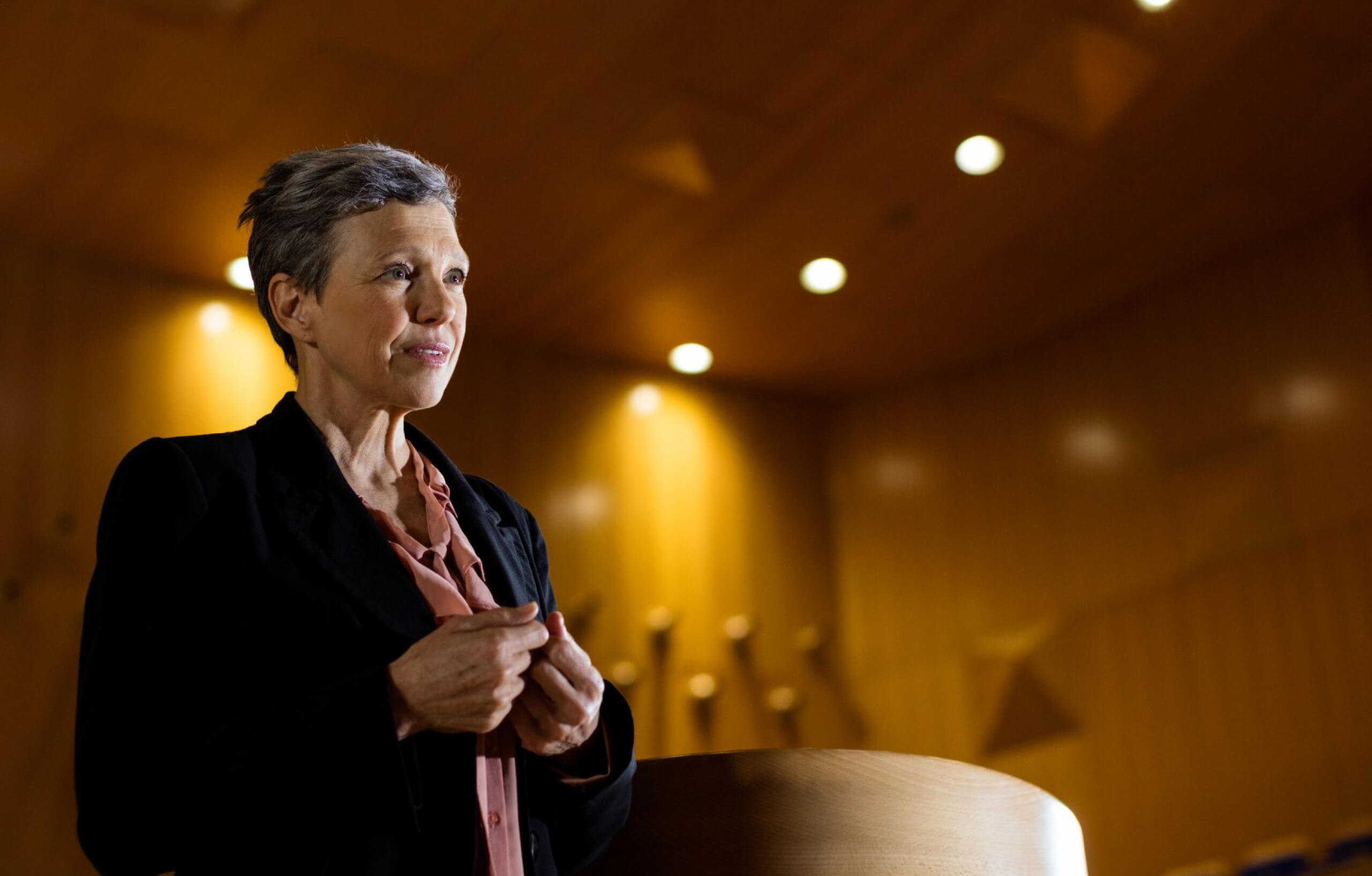 A middle aged woman speaking in an auditorium