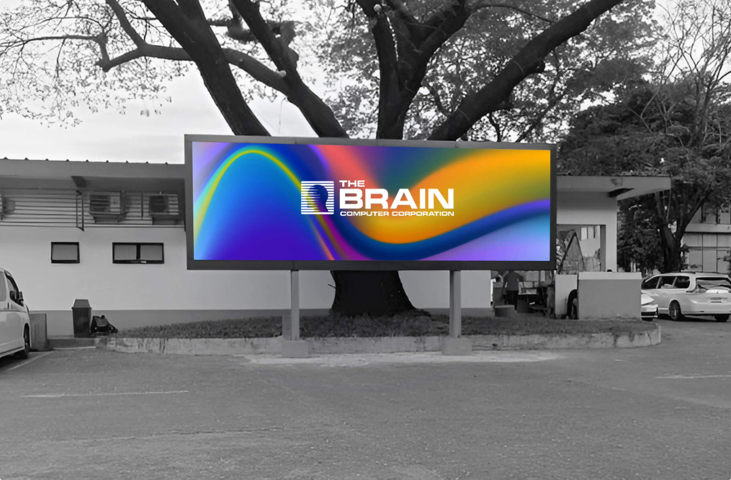 Colorful digital billboard with The Brain Computer Corporation logo in a mostly black-and-white parking area.
