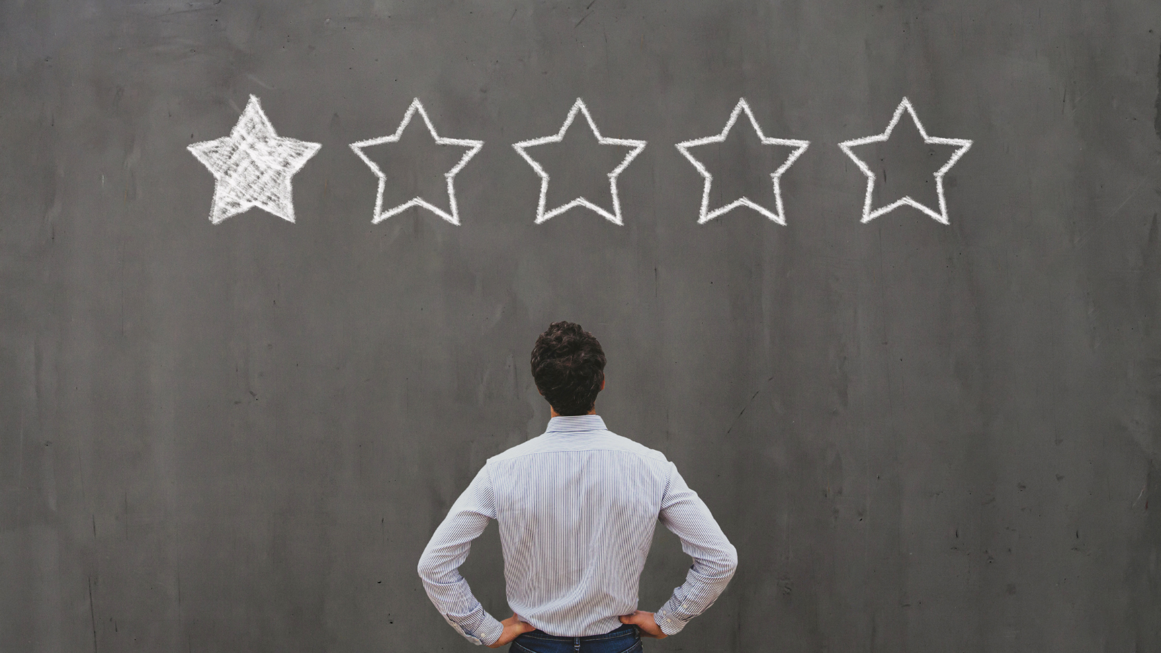 Man in a striped shirt with hands on hips facing a chalkboard wall with five chalk-drawn stars overhead and only the first filled in, illustrating the one-star review every field service operator dreads and the discipline that prevents it
