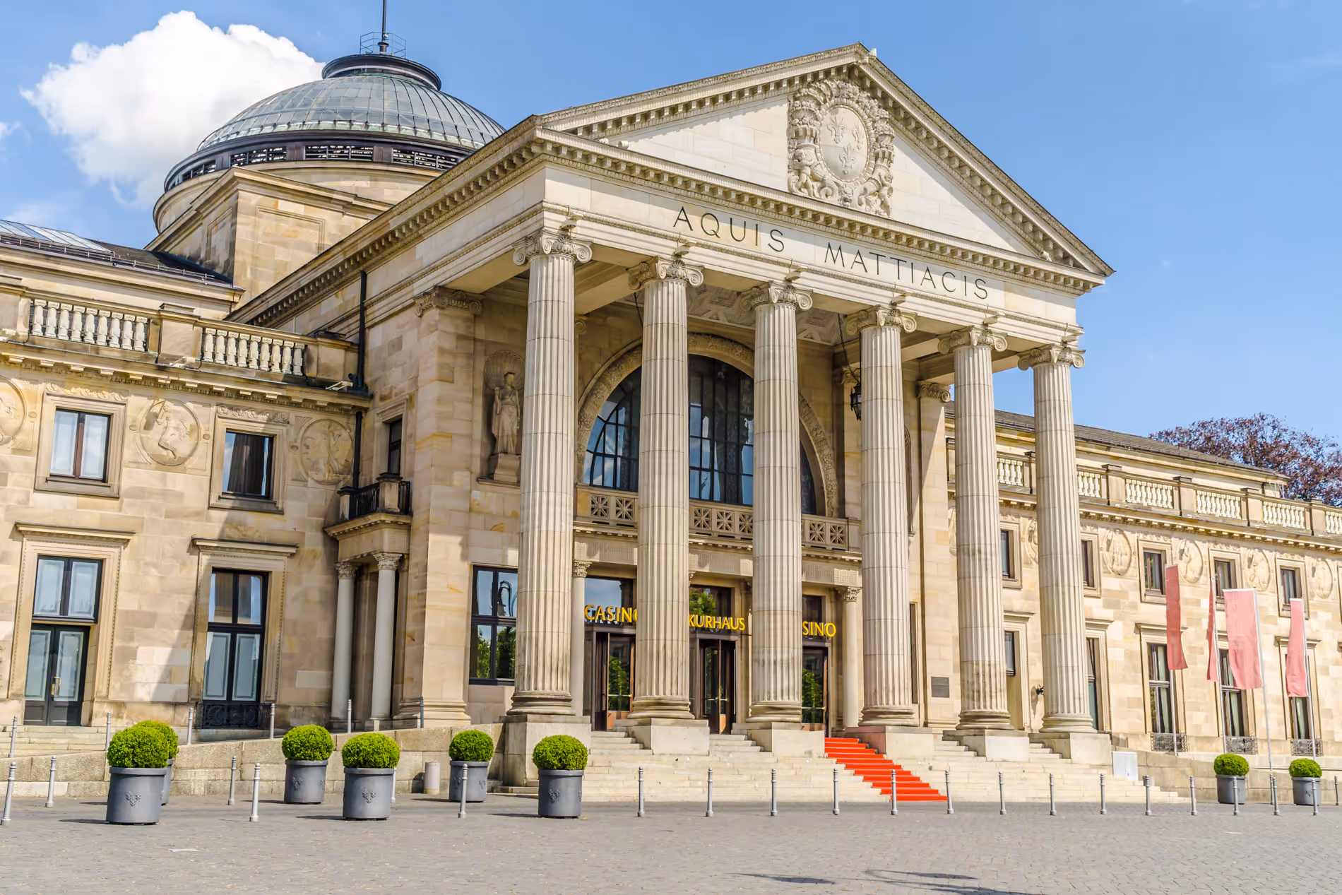 Das Kurhaus in Wiesbaden mit Säulen, rotem Teppich und Inschrift Aquis Mattiacis am Eingang.