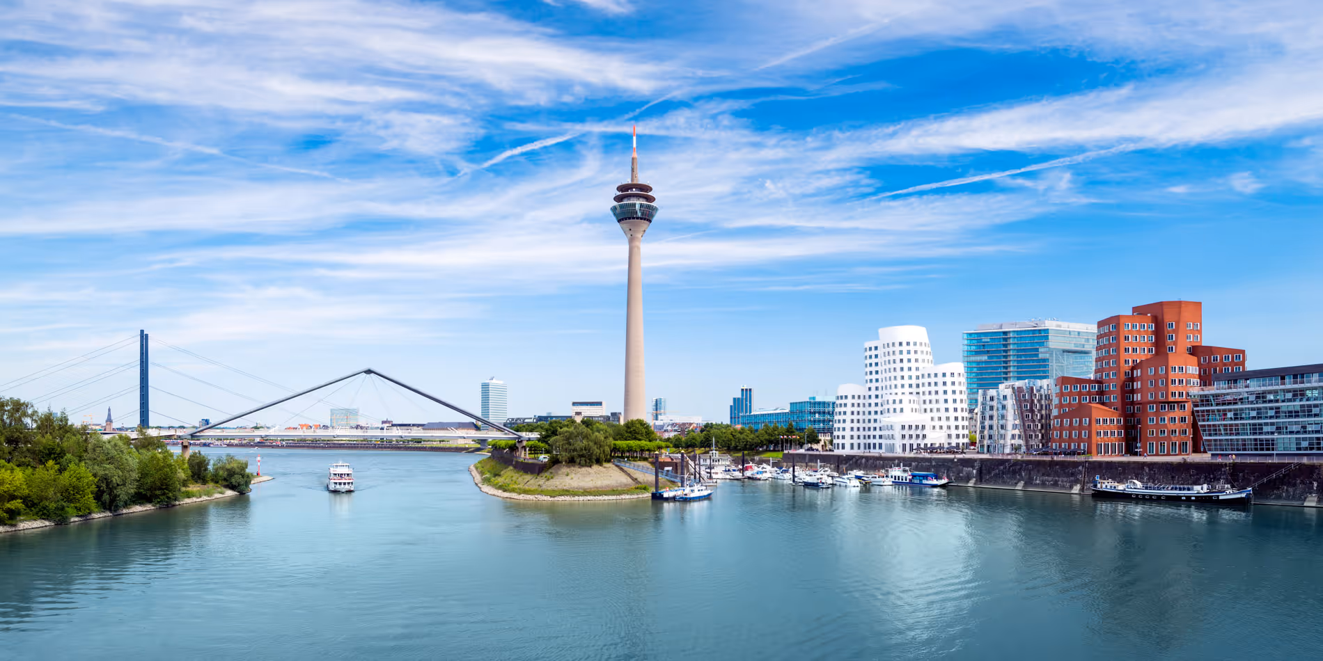 Panoramablick auf den Rhein mit der Rheinturm-Stele, moderner Architektur und einer Brücke in Düsseldorf.