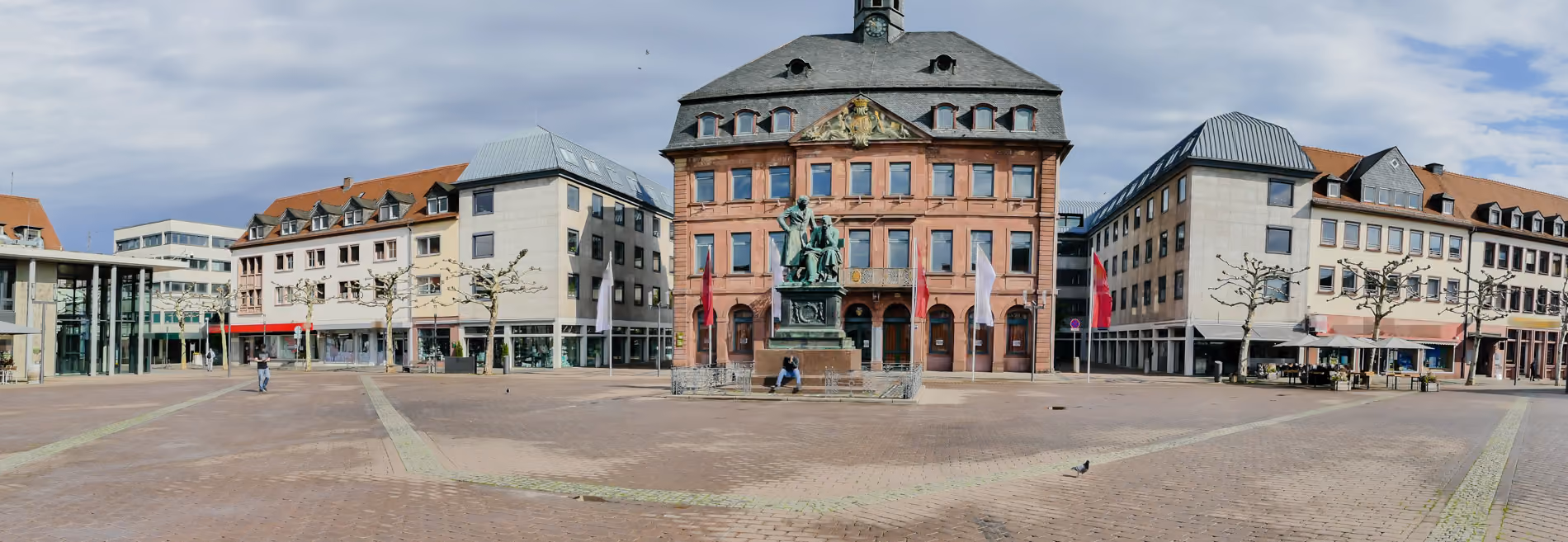Stadtplatz Hanau mit historischer Statue und Rathaus bei bewölktem Himmel.