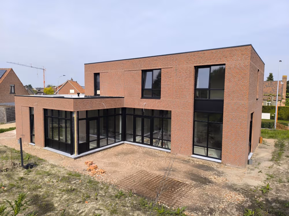 Moderne kubuswoning in ruwbouwfase met rode bakstenen gevel en plat dak