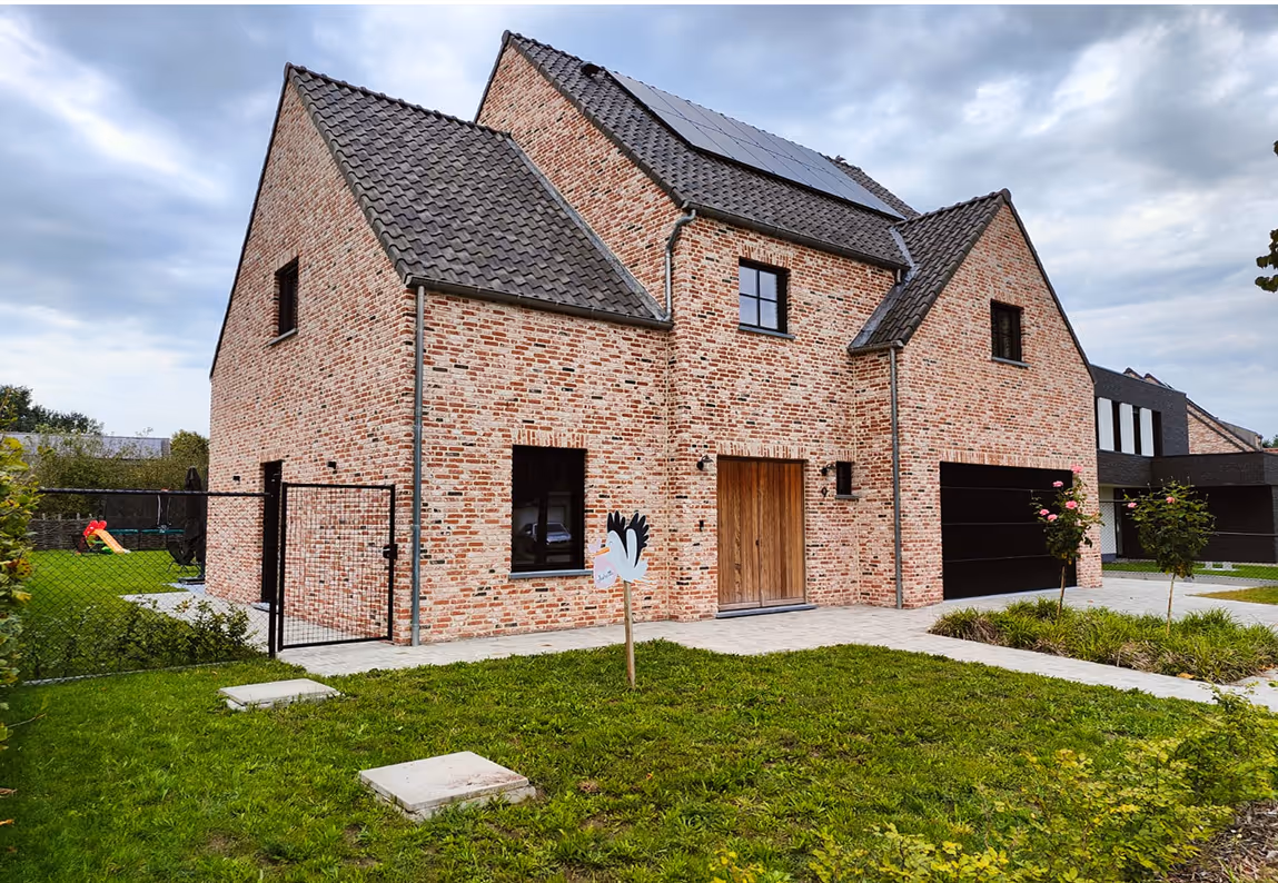 Moderne nieuwbouwwoning met bakstenen gevel, hellend dak, zonnepanelen en aangelegde voortuin