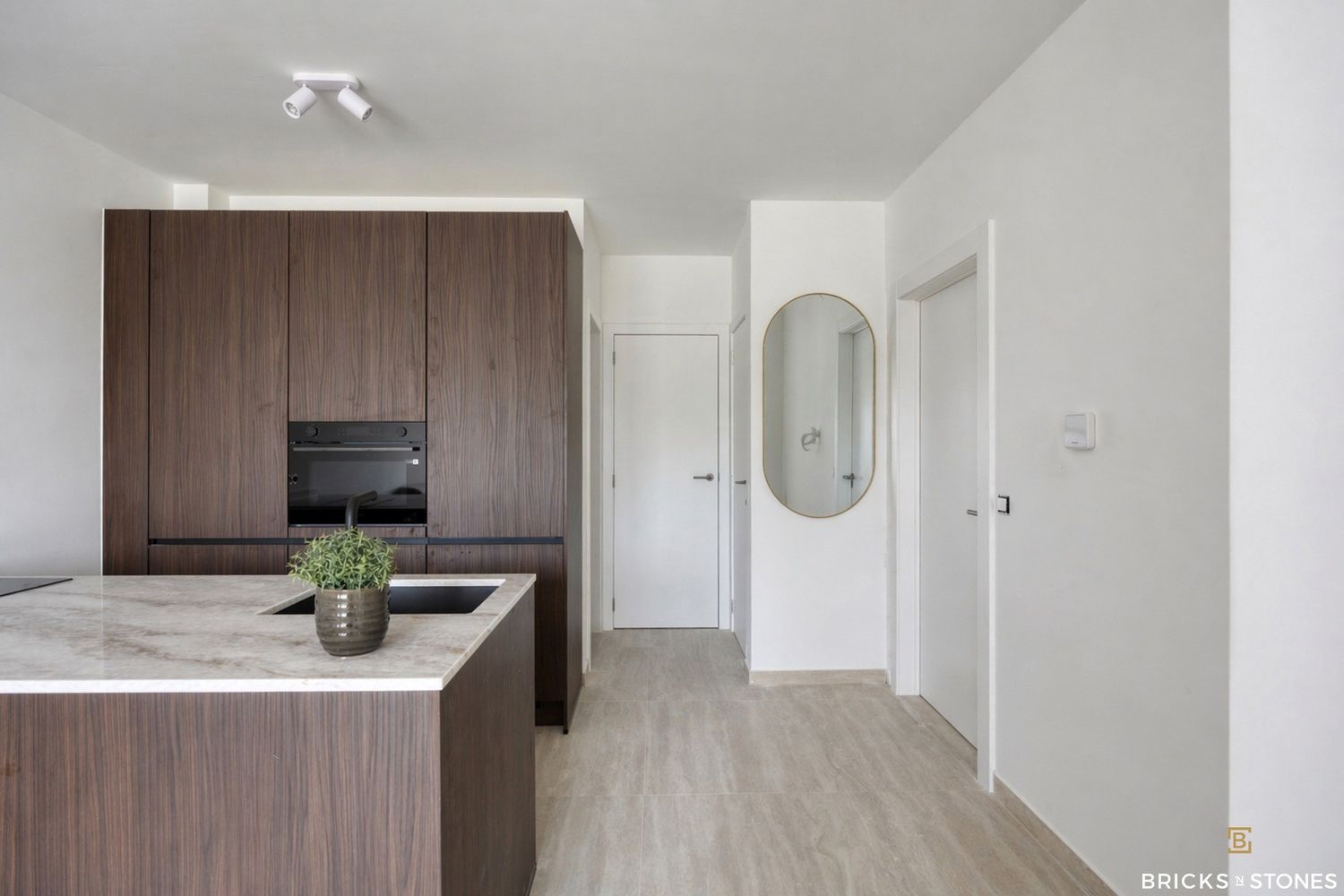 Strak keuken-interieur met donkerhouten kasten en marmeren werkblad in nieuwbouwappartement Gildestraat Merksem