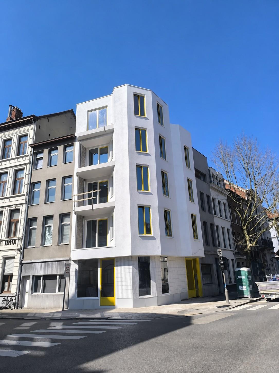Modern stadsappartementsgebouw met witte gevel en gele schrijnwerkaccenten in Van De Wervestraat Antwerpen