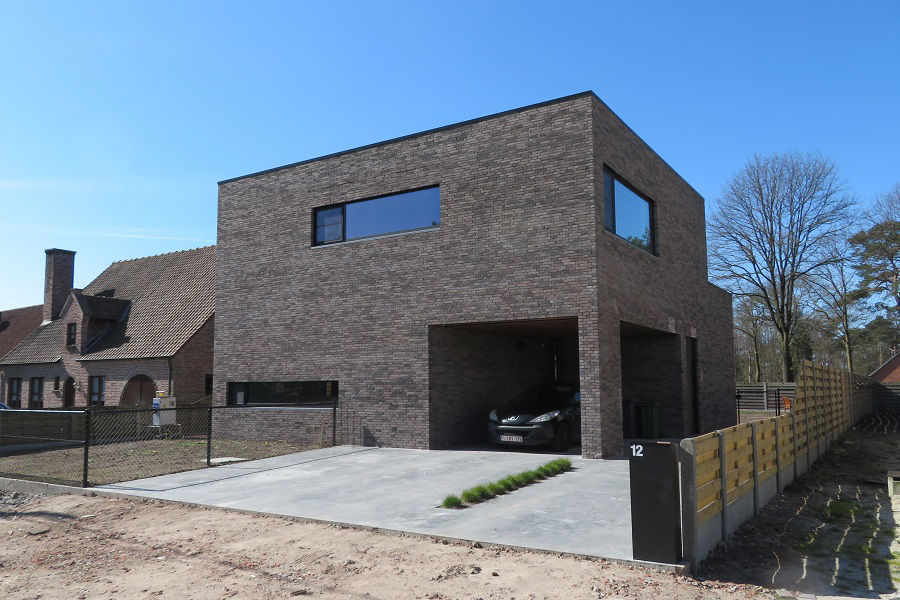 Moderne kubuswoning met donkere bakstenen gevel en overdekte oprit te Oud-Turnhout