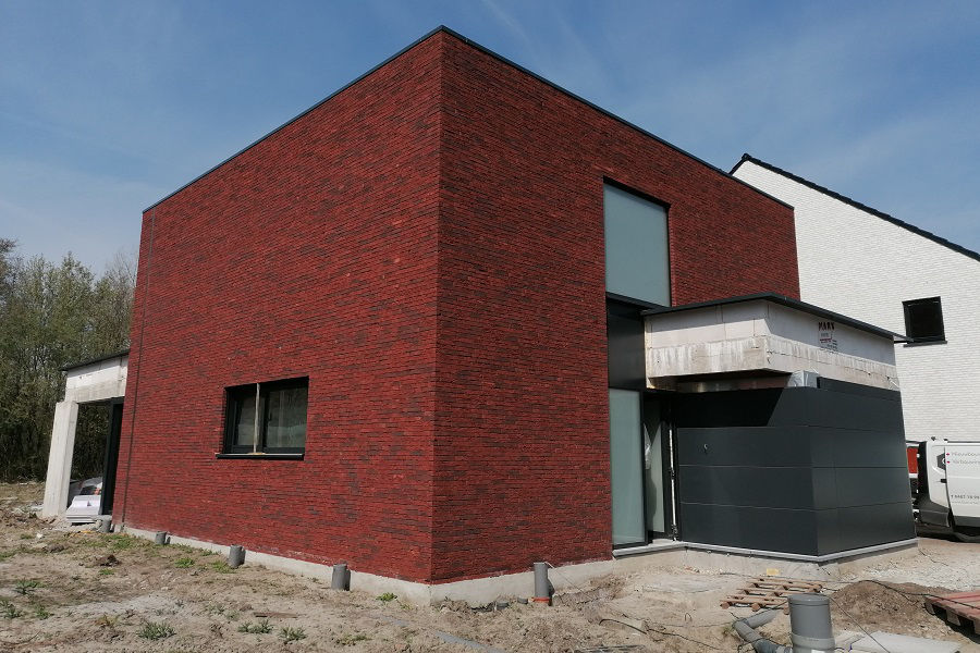 Moderne kubuswoning met rode bakstenen gevel en zwart aluminium ramen en deuren te Mol