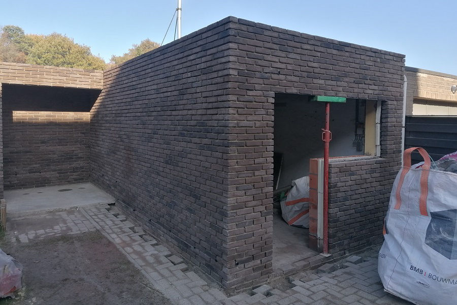 Donkere bakstenen tuinmuur met poortopening in ruwbouwfase – Marie Van Hongarijestraat Turnhout
