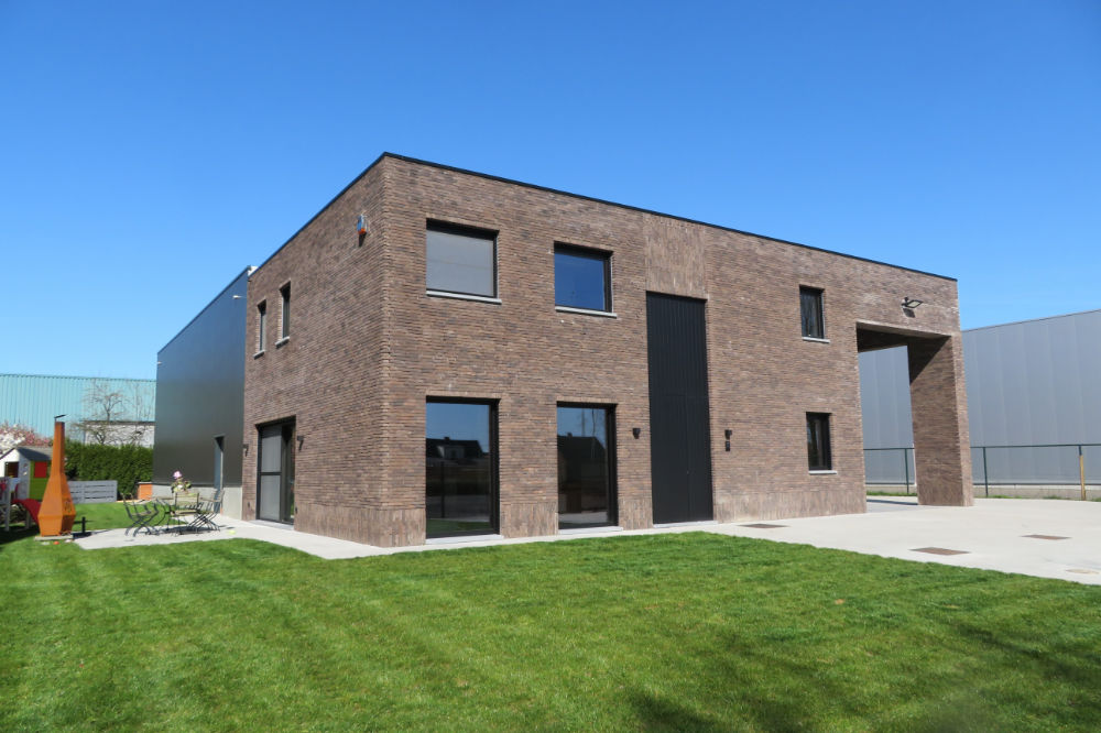 Moderne kubuswoning met donkere bakstenen gevel en strak plat dak te Beerse