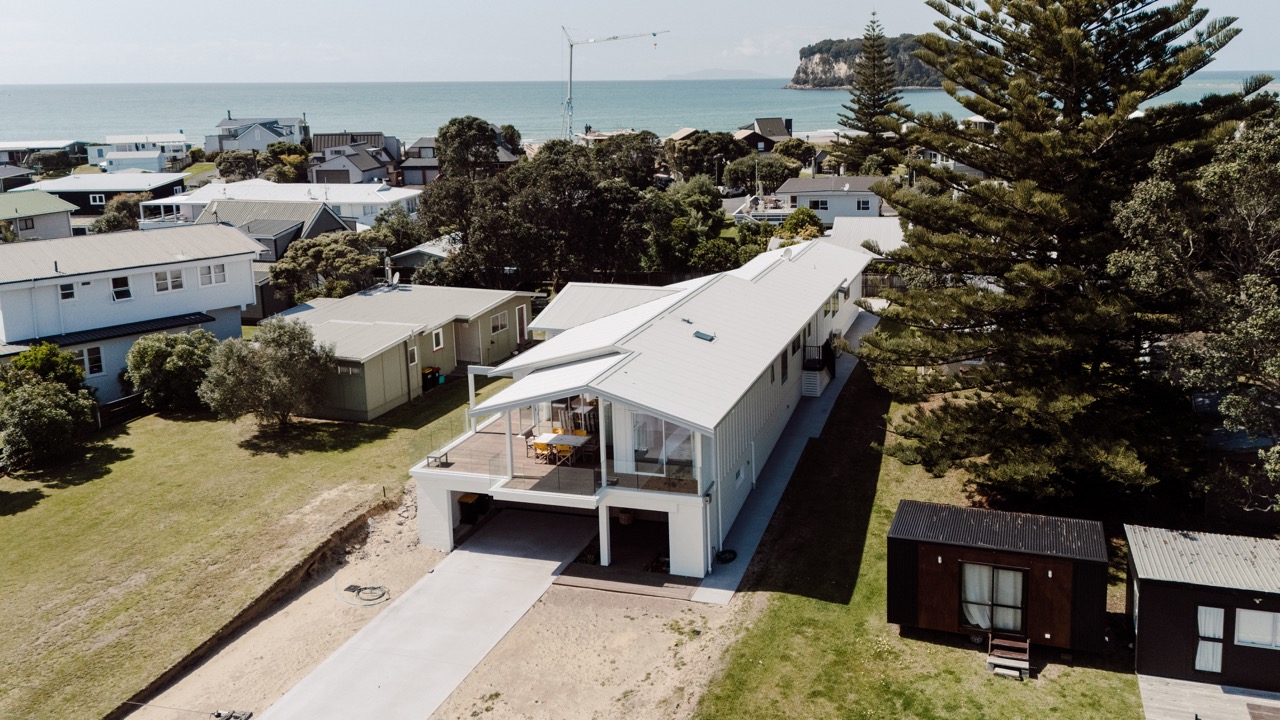 Aerial view of the completed home at 124 Diana Ave, Whangamatā, with the beach beyond
