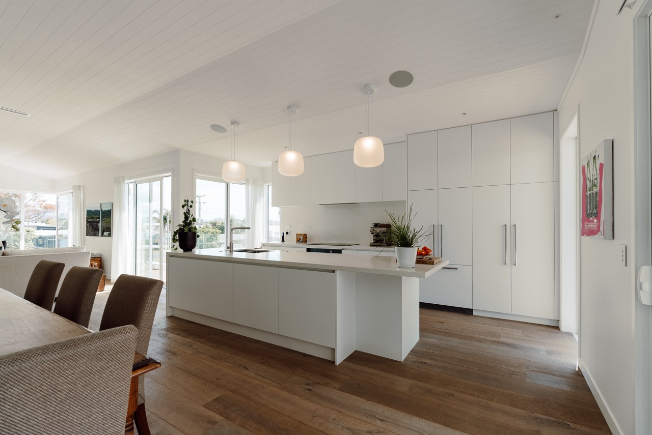 White kitchen with island and timber flooring at 124 Diana Ave, Whangamatā