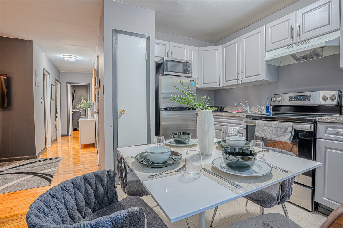 A modern kitchen with white cabinets, stainless steel appliances, and a cozy dining setup.