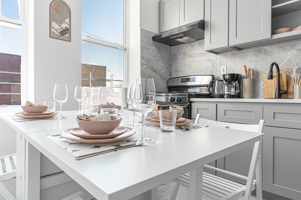Eat-in kitchen set for the group — full-size stove, prep space, and dishware ready for home-cooked meals near LaGuardia.