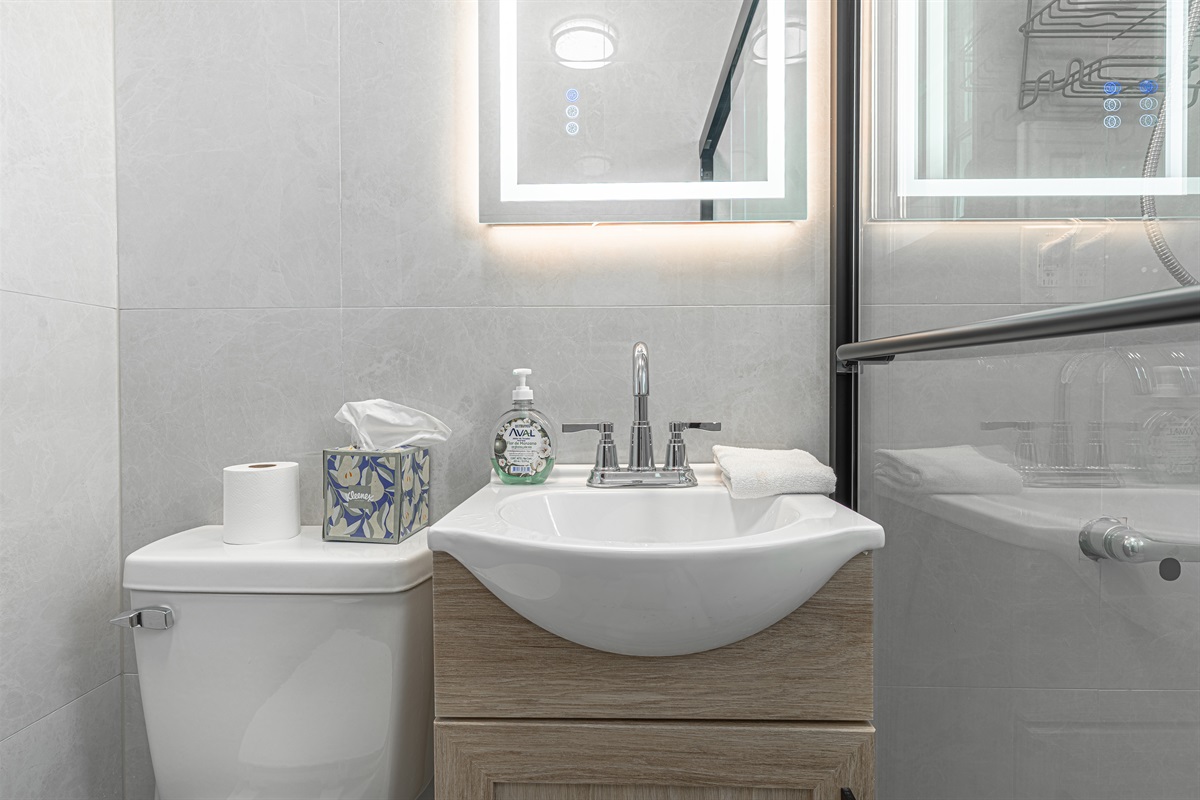 Bright full bathroom with walk-in glass shower and stocked vanity — comfortable and hassle-free.