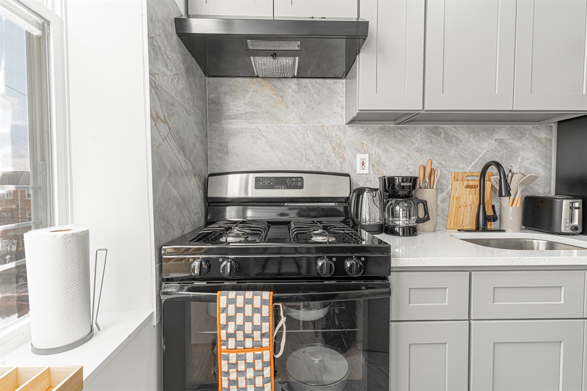 Modern kitchen with full-size stove, coffee maker, and ample white cabinets — everything you need to cook in comfortably