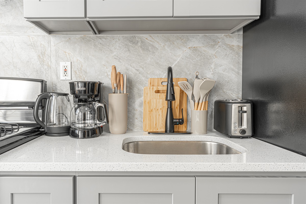 Sleek kitchen counter with marble backsplash, sink, and everyday appliances — functional and move-in ready.