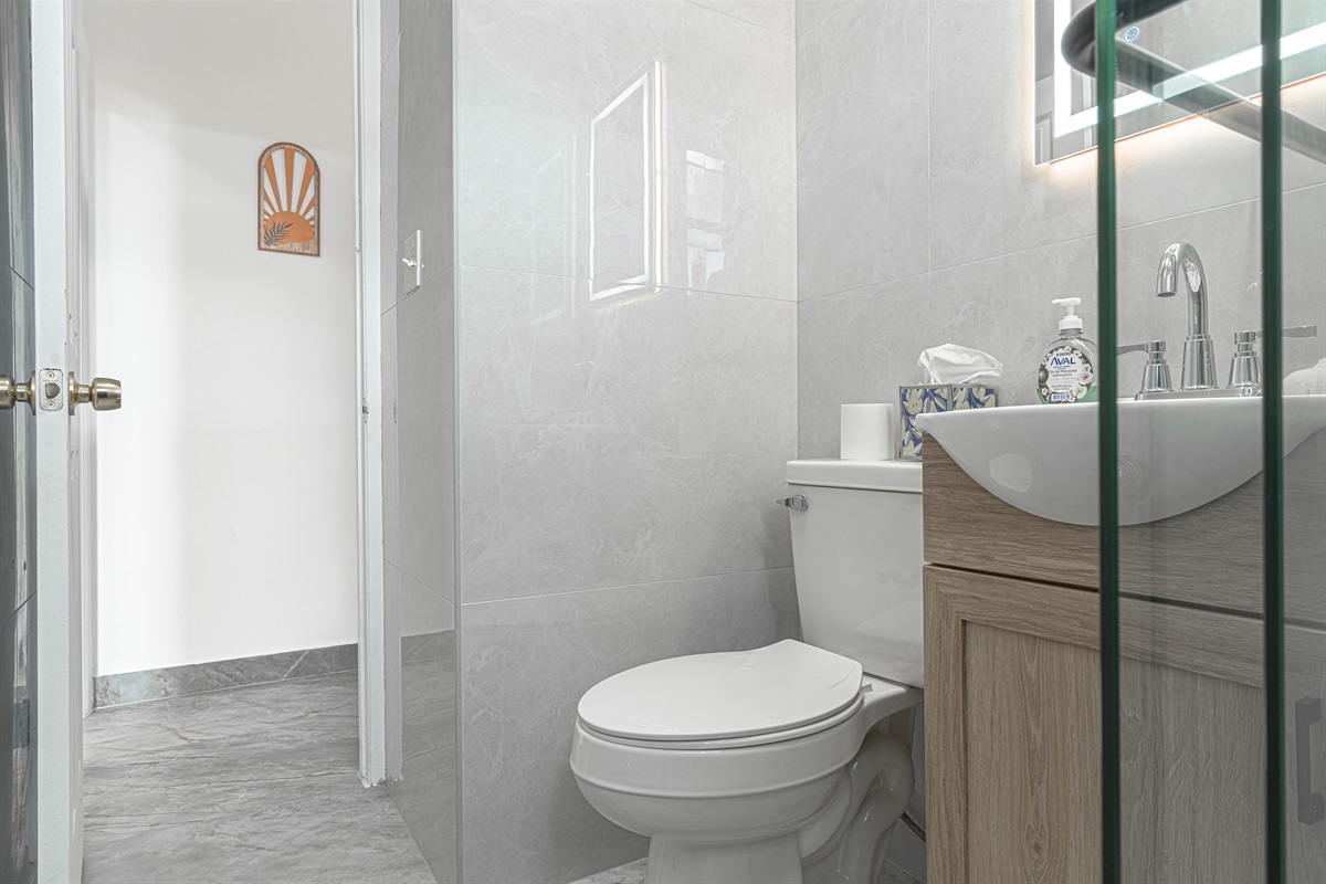 Clean, modern bathroom with a glass-enclosed shower, wood vanity, and fresh towels — spotless and ready for you.