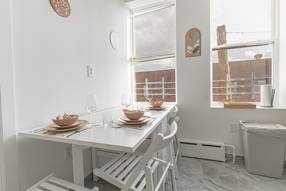 Sunlit kitchen and dining nook with two windows — a cheerful spot for morning coffee and shared meals.