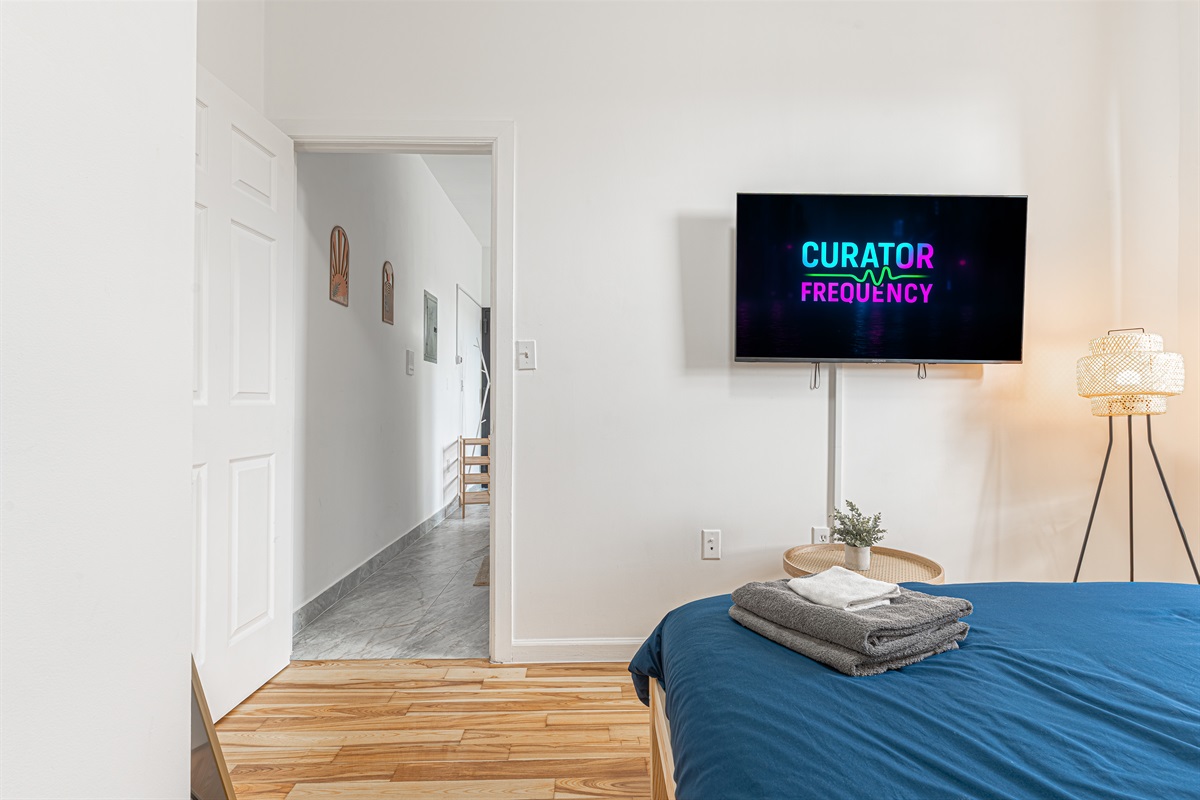 Comfortable bedroom with smart TV and cozy bedding — unwind and stream after a day exploring NYC.