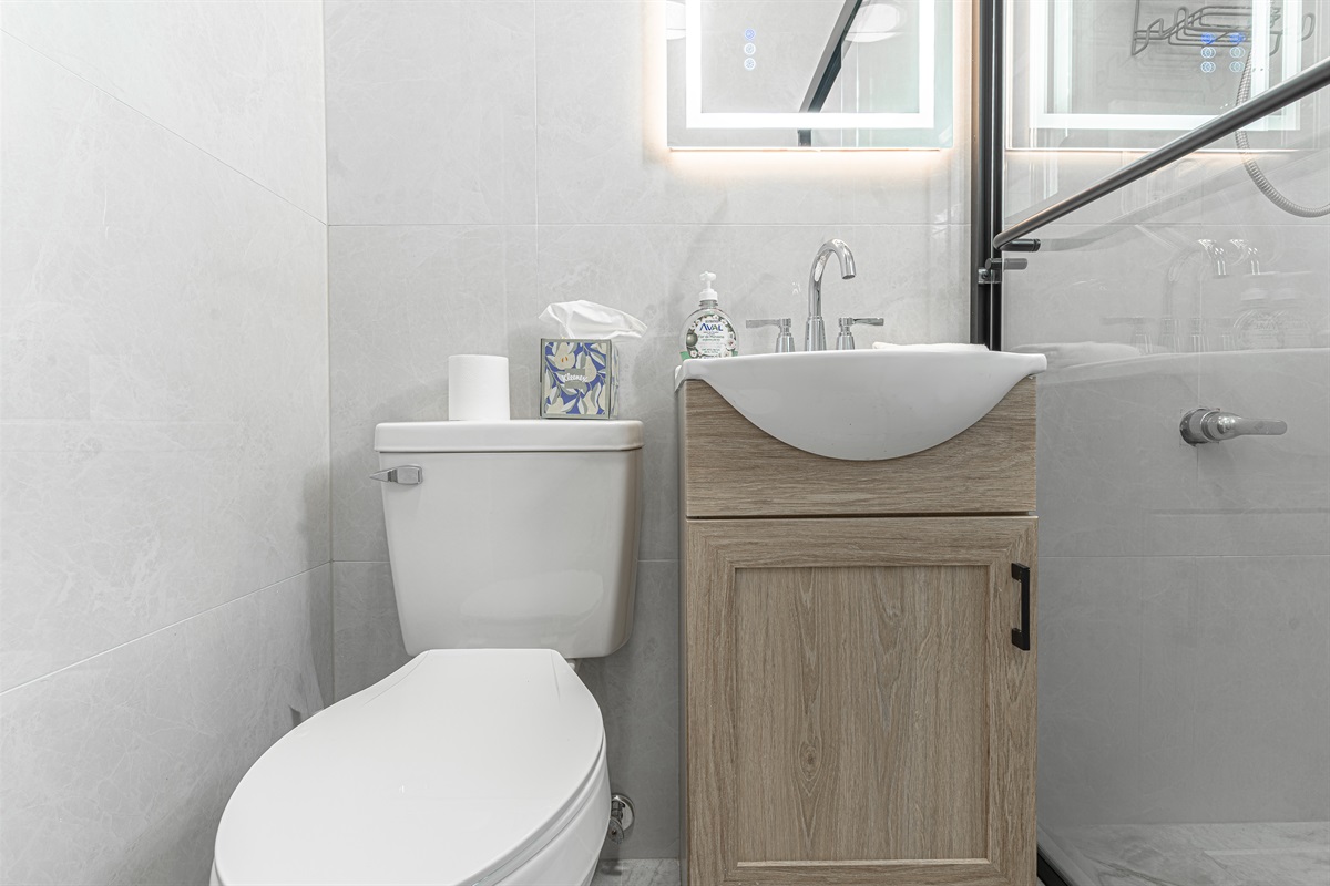 Modern bathroom with glass shower and wood vanity — convenient and immaculately kept.