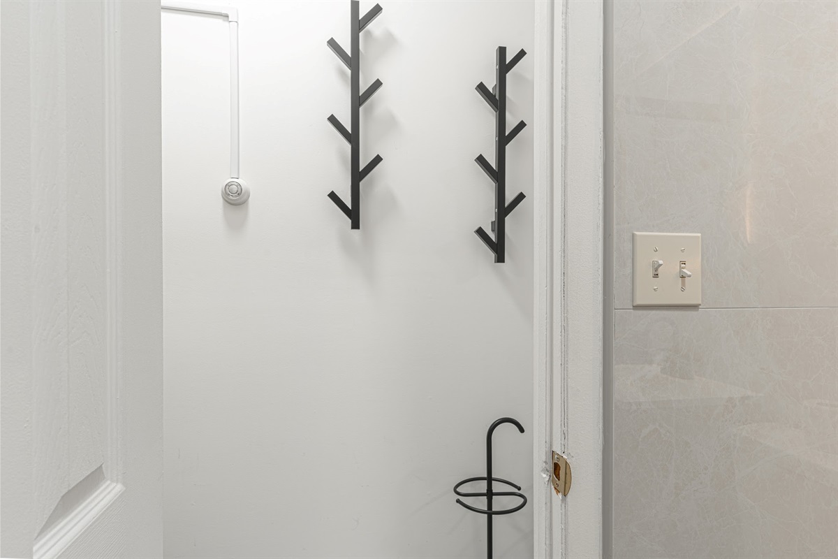 Clean, modern bathroom with sleek tile and wall hooks — fresh and ready for your arrival.