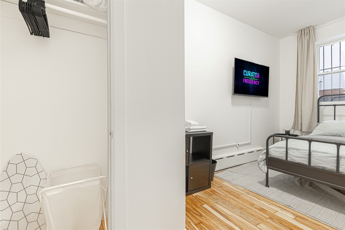 Bright bedroom with a wall-mounted TV and fresh bedding — settle in and stream after a long day.
