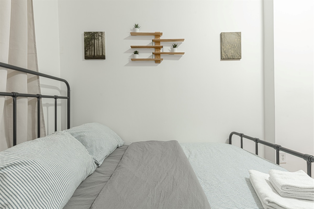 Restful primary bedroom with a plush bed and fresh linens — quiet, comfortable sleep in Queens.