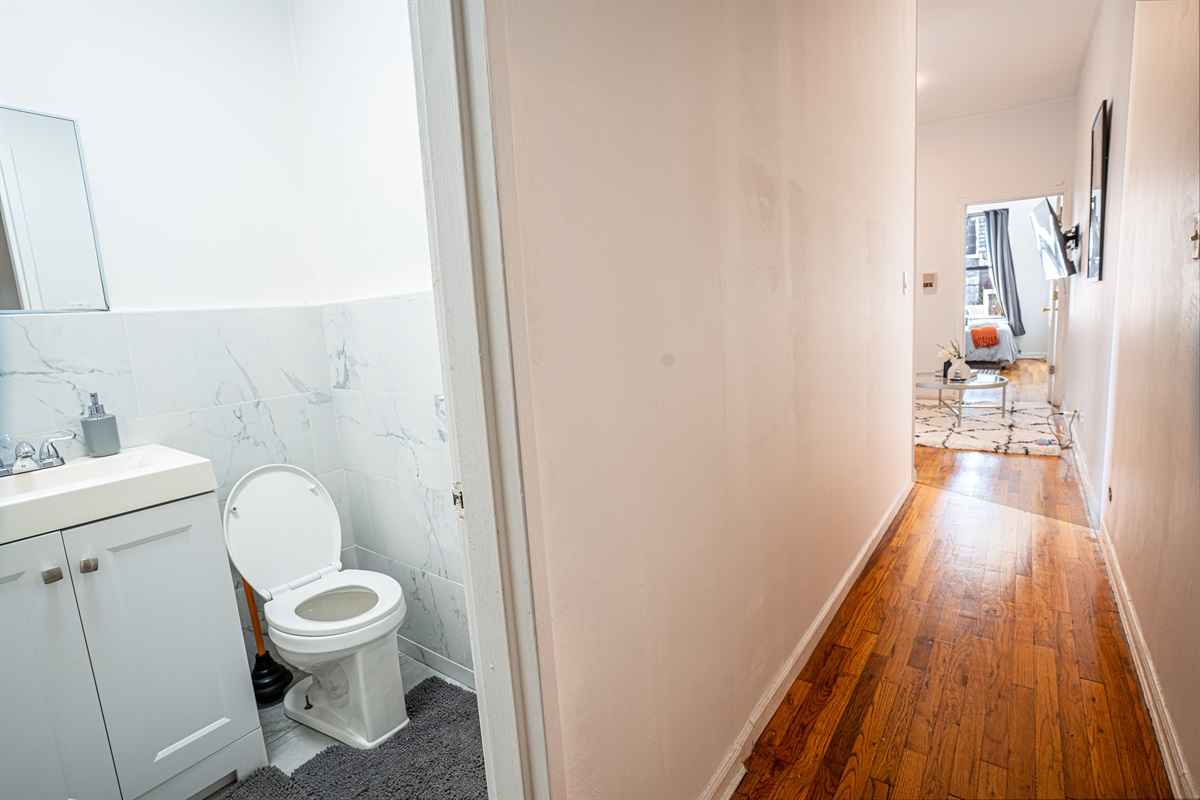 Hallway view with bath access and warm hardwood floors