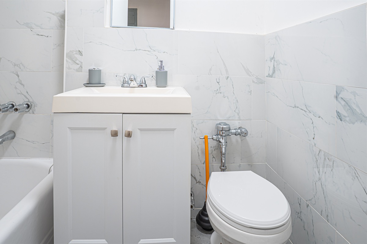Modern tiled bathroom with vanity, tub, and clean finishes.