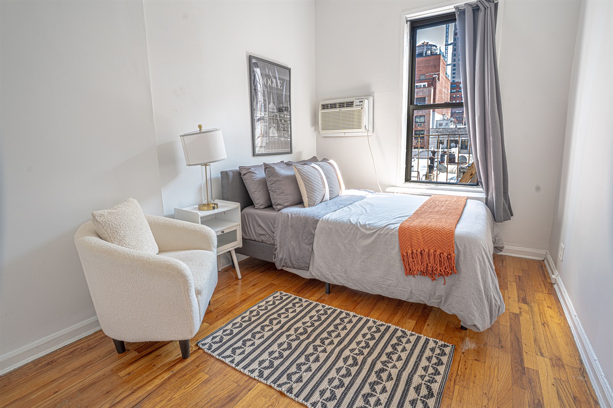 Bright, stylish room with full bed, chair, and city views