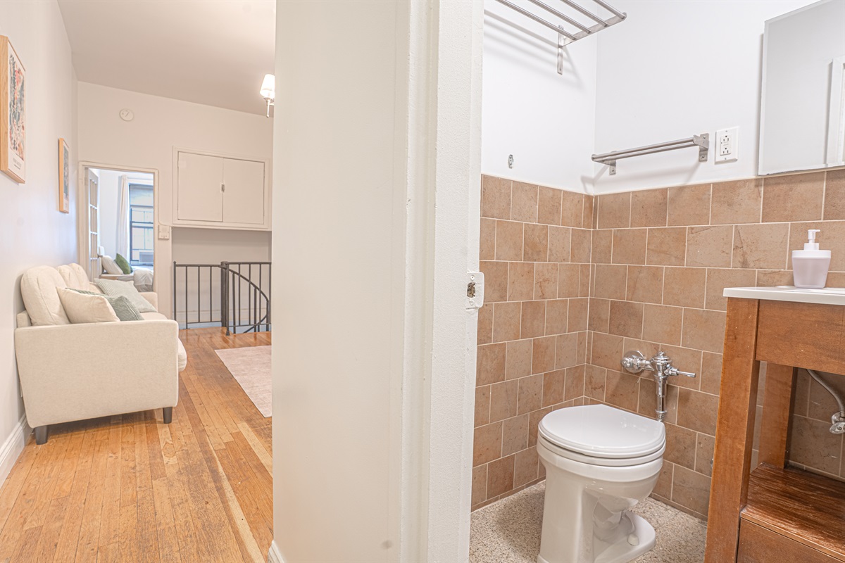 Full bathroom with a wood vanity and warm tiled walls — comfortable and convenient for your stay.