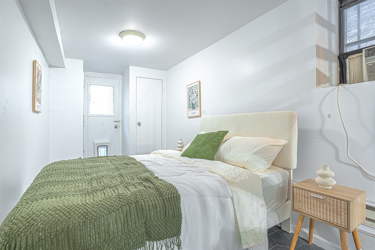 Comfortable second bedroom with a soft headboard and fresh linens — great for family or friends sharing this 2BR.