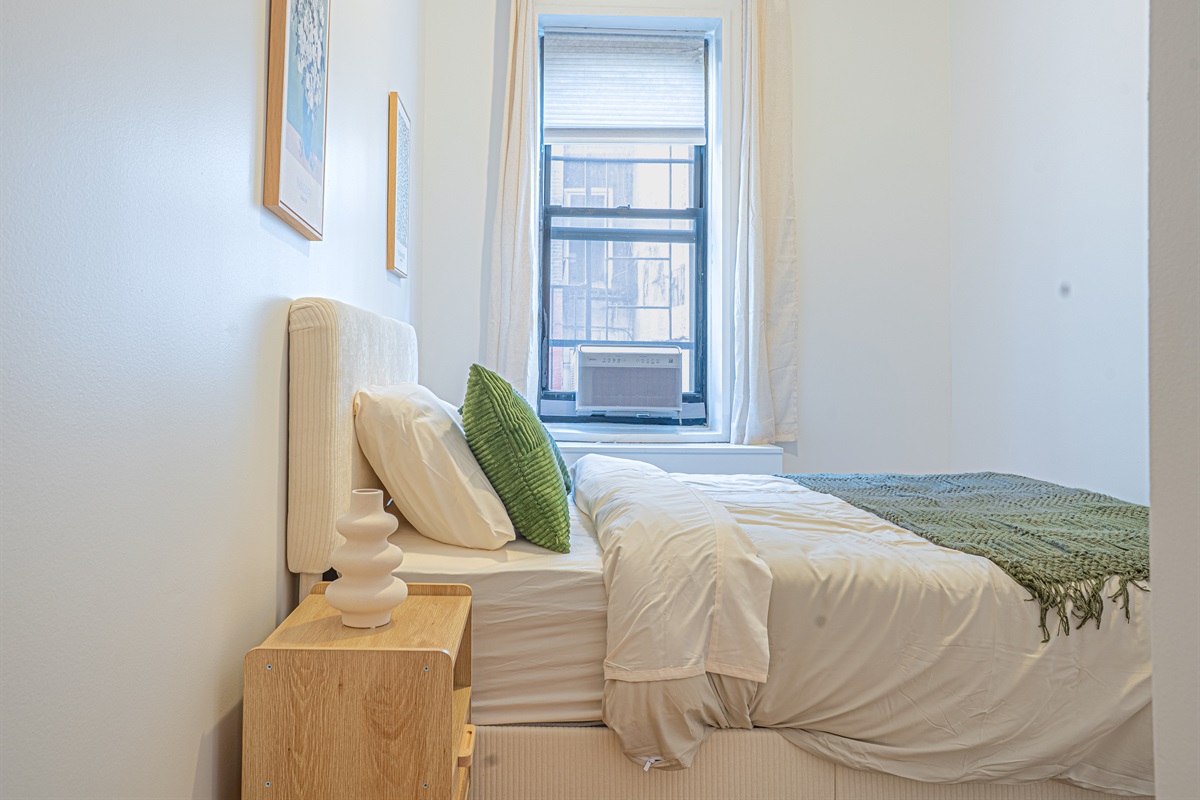 Serene bedroom with a plush bed, fresh linens, and bright natural light — a restful retreat in this Upper East Side home
