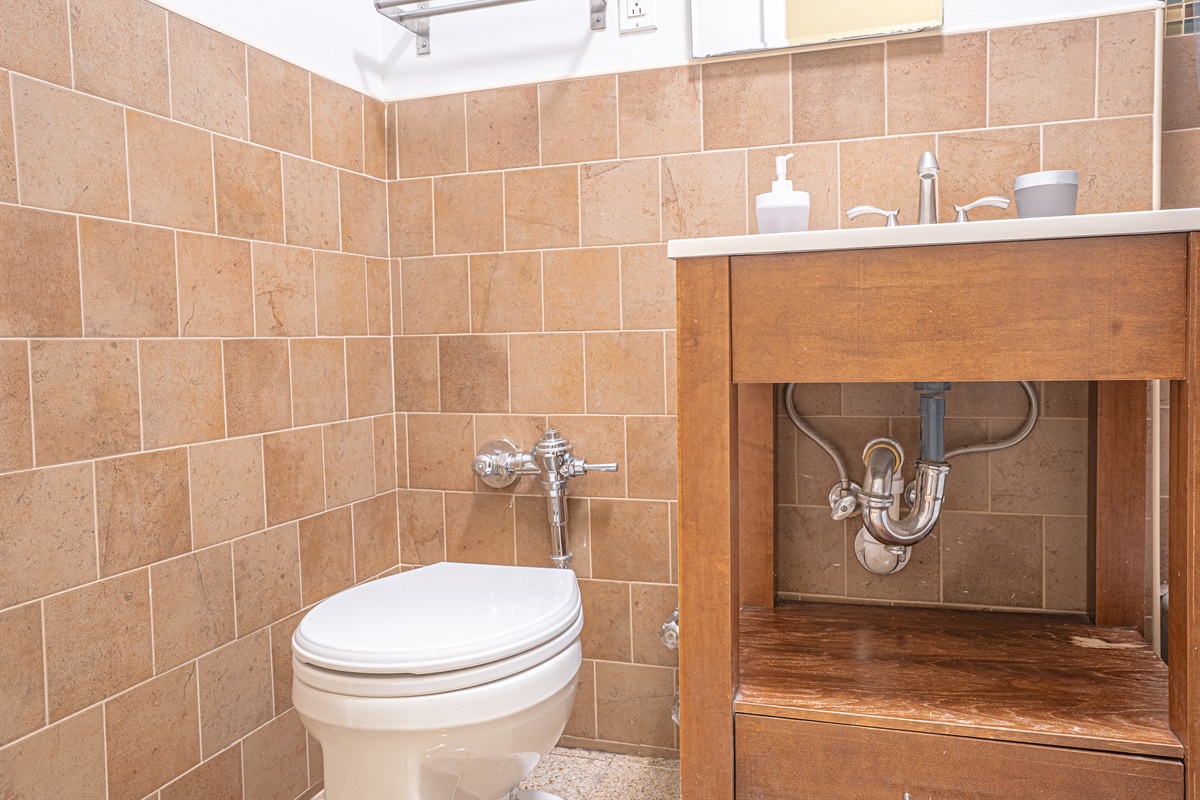 Tiled bathroom with a wood vanity and handy under-sink storage — fresh towels and essentials within easy reach.